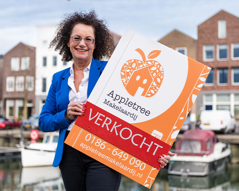 Makelaar bij Appletree Makelaardij dat een verkochtbord vasthoudt